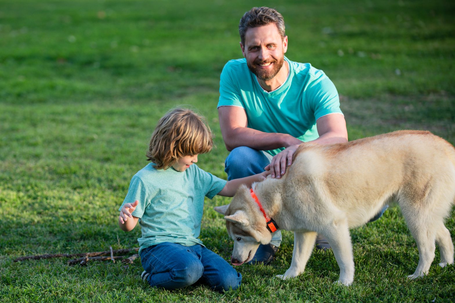 Padre e hijo con perro mascota relajándose en la naturaleza en el parque